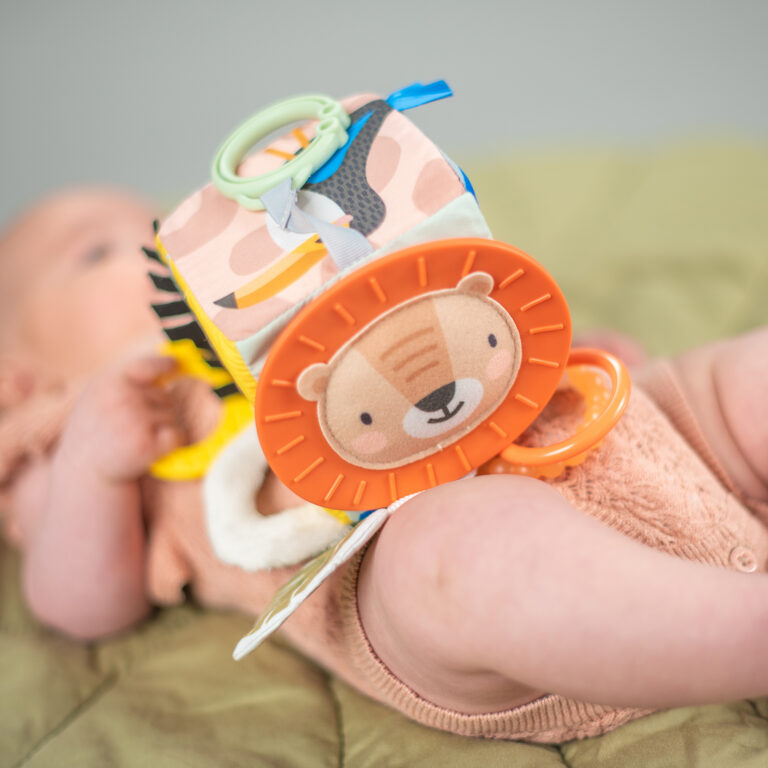 מתנה ליולדת בן המכילה סל צבעוני קלוע המכיל קוביית סקרנות צבעונית אינטראקטיבית, שלישיית חיתולי טטרה ובובה מנגנת נתלית של חברת פלייגרו
